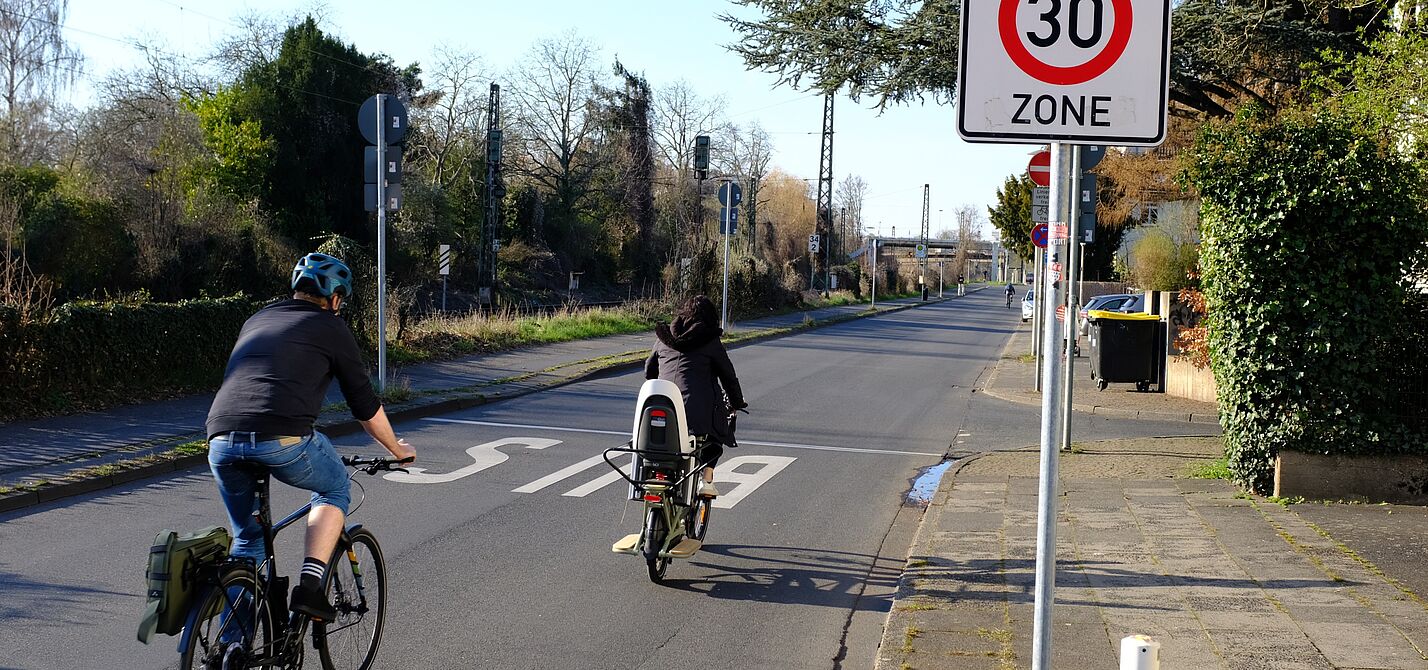Infrastruktur_NRW_Bonn_ADFC_NRW__30 Zwei Radfahrer fahren an einem Tempo 30 Schild vorbei.
