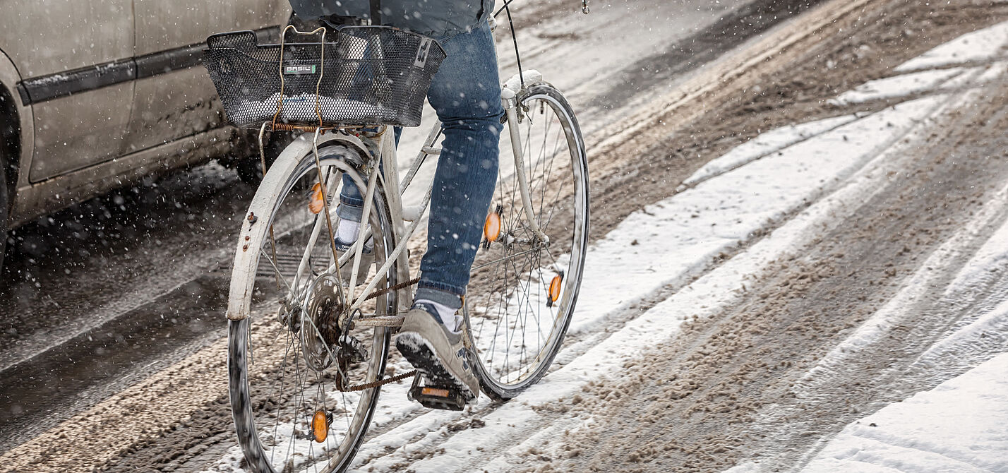 Radfahren im Winter Ein Radfahrer fährt auf einem ungeräumten Radweg durch Schnee.
